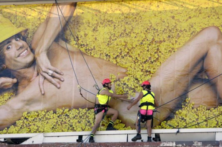 Gwiazdy filmu, TV... - Bruno. Mężczyźni w różowych szortach i kaskach instalują baner reklamowy filmu.jpg